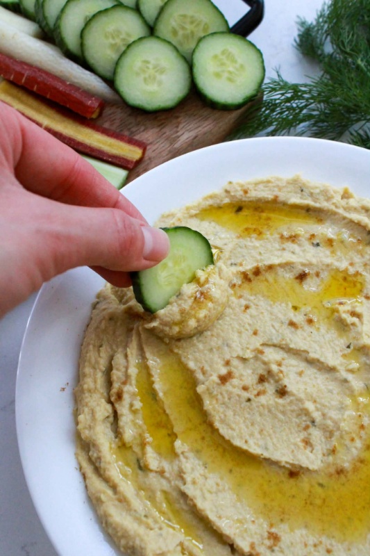 Dipping a Cucumber in Dill Pickle Hummus