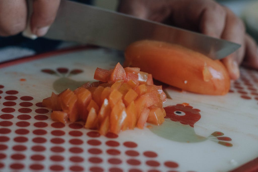 Hands chopping the product on a decorative cutting board in a kitchen setting.